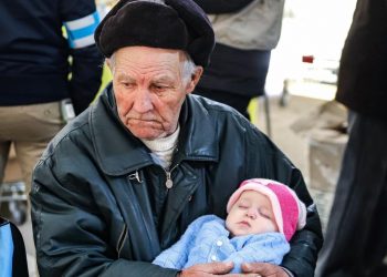Дідусь, який колише свою онучку, тікаючи з-під обстрілів (відео)