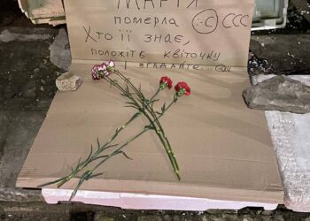 Люди кладуть квіти до місця, де торгувала бабуся